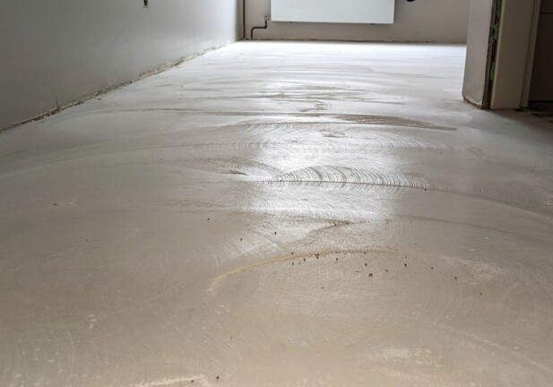 Unfinished hotel room floor with smoothing marks and neutral walls, under renovation for updated guest accommodations