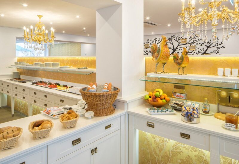 Heller Frühstücksbuffet mit frischem Brot, gekochten Eiern, Obst, Aufschnitt, Gewürzen und prunkvollen goldenen Kronleuchtern