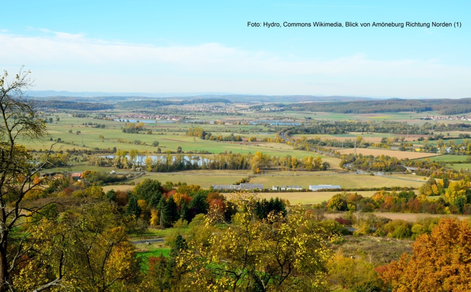Panoramablick auf die Landschaft mit sanften Feldern, verstreuten Bäumen, entfernten Dörfern und klarem blauem Himmel an einem frischen Tag