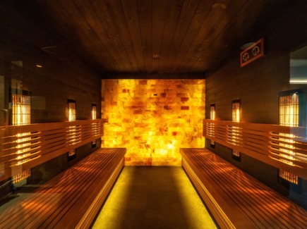 Деревянная сауна с подсвеченной соляной стеной, ярусными скамьями и тёплым янтарным освещением