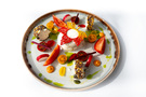 Gurmánská předkrm: krémová burrata s červeno‑žlutou ozdobou, sýrové rolky obalené semínky a cherry rajčátky