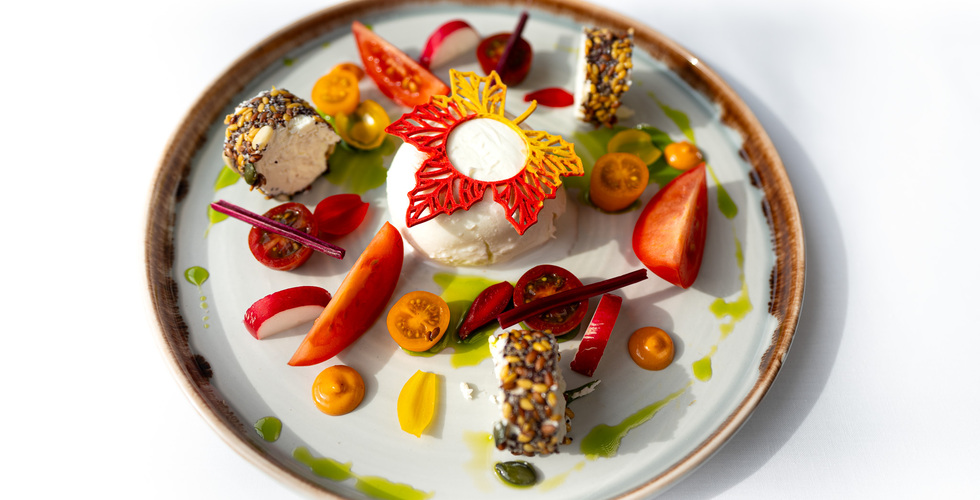 Gurmánská předkrm: krémová burrata s červeno‑žlutou ozdobou, sýrové rolky obalené semínky a cherry rajčátky