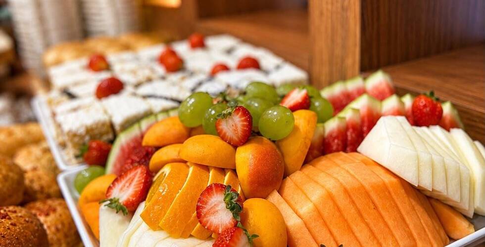 Snídaňová ovocná mísa na bufetu s plátky cantaloupe, medového melounu, jahod, hroznů a meruněk vedle čerstvých rohlíků.