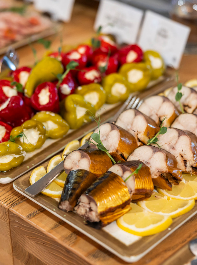 Buffetplatte mit geräucherten Fischscheiben auf Zitronenscheiben und rot‑gelben, mit Creme gefüllten Paprika