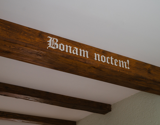 عارضة خشبية سقفية ريفية مع نقش قوطي أبيض 'Bonam noctem!'