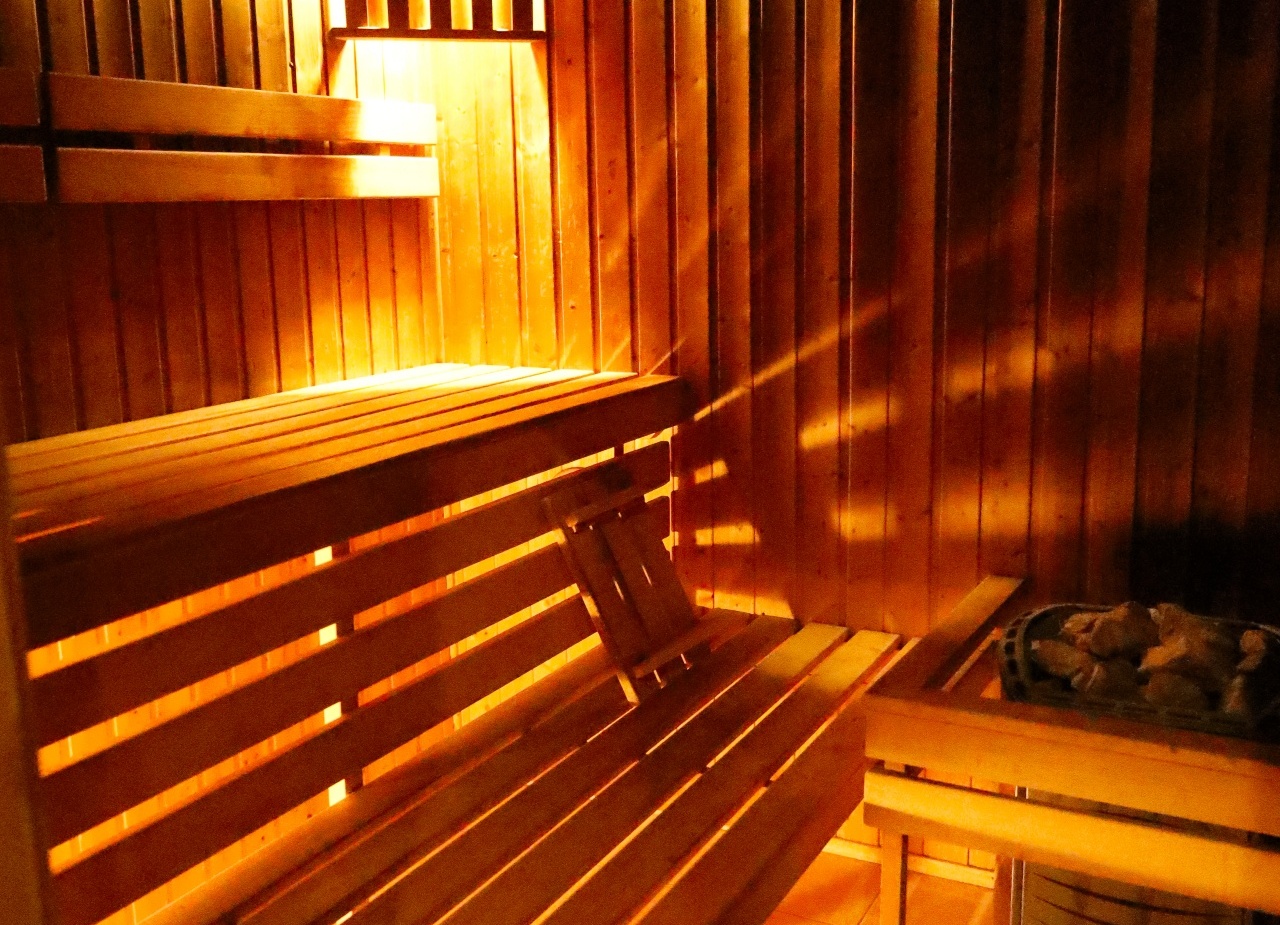 Drewniana sauna z wielopoziomowymi ławami, ciepłym bursztynowym oświetleniem i piecem z kamieni — relaks w strefie spa.