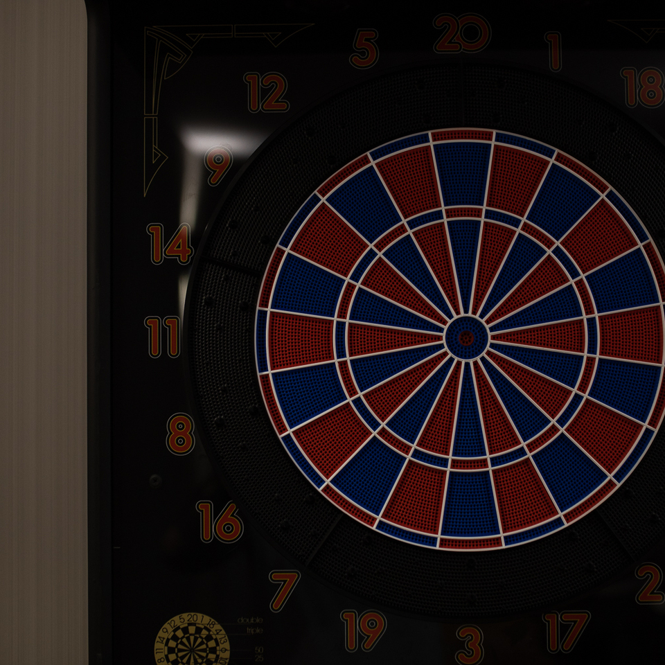 Elektronische Dartscheibe mit rot-blau segmentiertem Ziel und nummeriertem schwarzem Rahmen, an dunklem Wandpanel montiert.