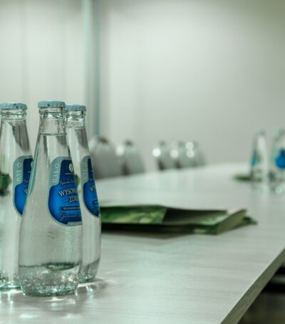 Konferencyjny stół z butelkami wody mineralnej i krzesłami, przygotowany na spotkanie biznesowe
