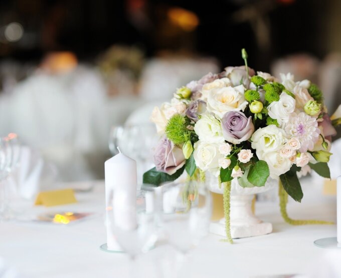 Elegancki ślubny stół z białymi świecami i bukietem róż, różowych i zielonych kwiatów w ozdobnym wazonie