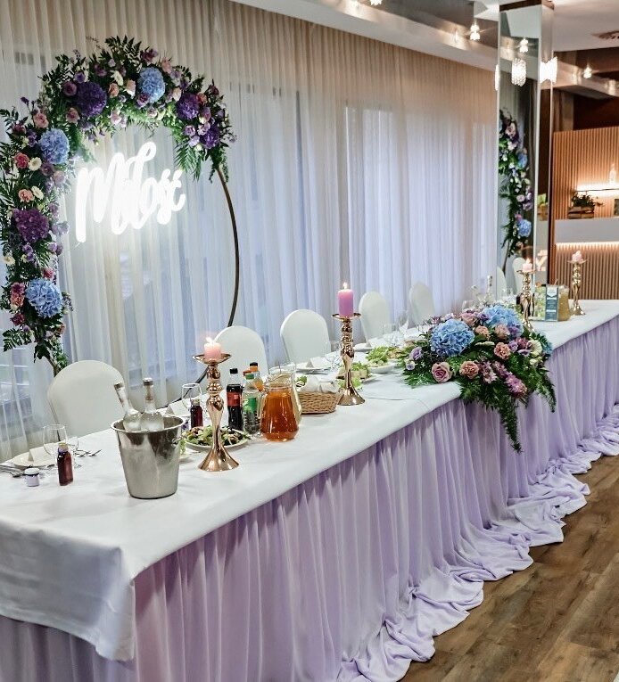 Elegancki stół weselny w hotelu, dekorowany kwiatami, świecami i napojami w luksusowej sali bankietowej