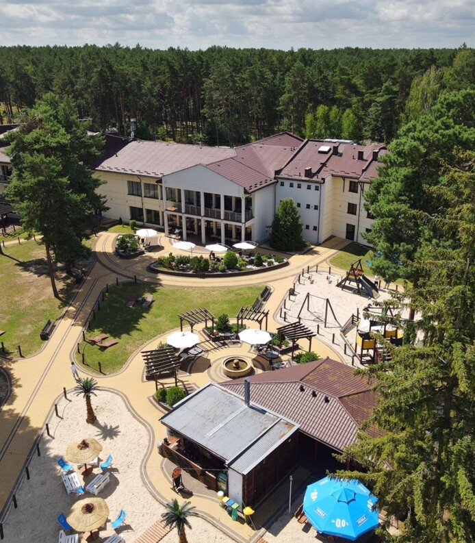 Hotel otoczony lasem sosnowym z tarasem, placem zabaw, ogrodowym miejscem do relaksu i letnim barem z parasolami