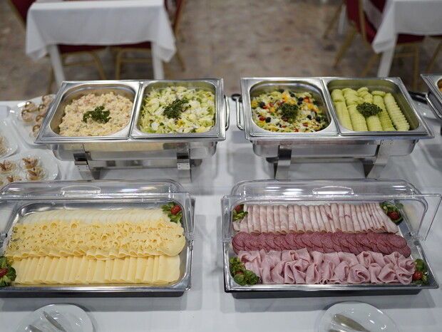 Hotelový bufet so studenými šalátmi, plátkami syra s dierkami a rôznymi druhmi nakrájanej šunky a salámy.