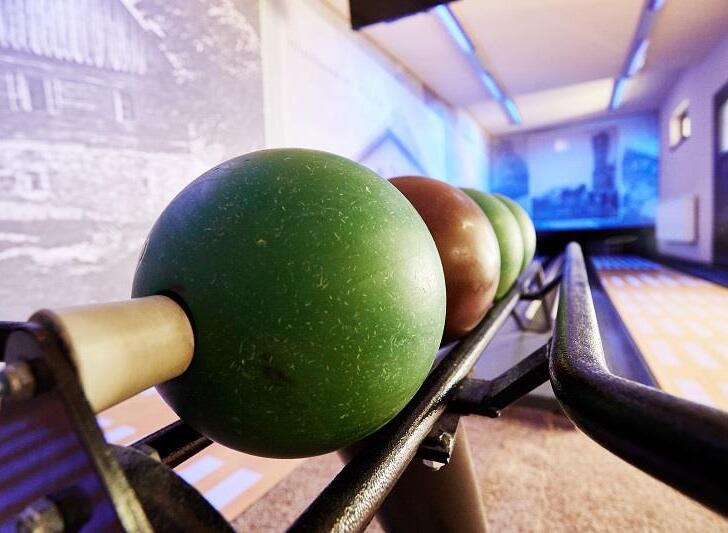 Hotelová kuželna s barevnými koulemi na stojanu, lesklými dráhami a atmosférickým modrým osvětlením