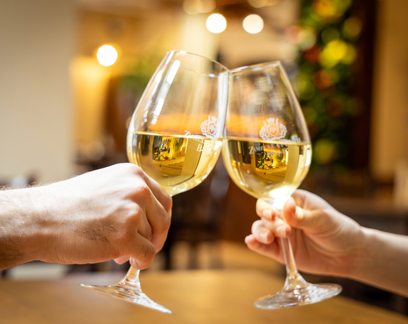 Přípitek bílým vínem při romantické večeři v útulné restauraci Hotelu Slunce Rýmařov v Jeseníkách.