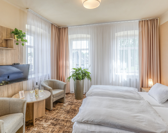 Světlý dvoulůžkový pokoj v Hotelu Slunce Rýmařov v Jeseníkách s pohodlnými lůžky, posezením, televizí a příjemnou atmosférou pro odpočinek.
