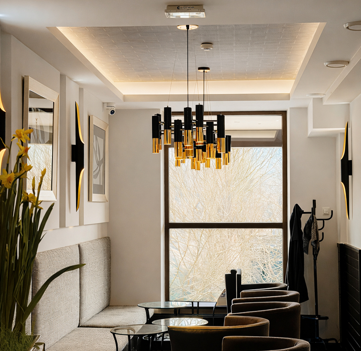 Elegancki hotelowy salon z przytulnymi fotelami, sofą przy ścianie, szklanymi stolikami i nowoczesnym złoto-czarnym żyrandolem