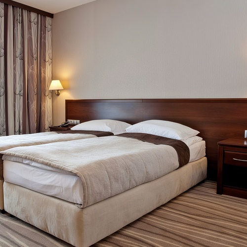 Dwuosobny pokój z dwoma łóżkami, drewnianym zagłówkiem, miękkimi narzutami, nocnymi stolikami, lampami i wzorzystymi zasłonami