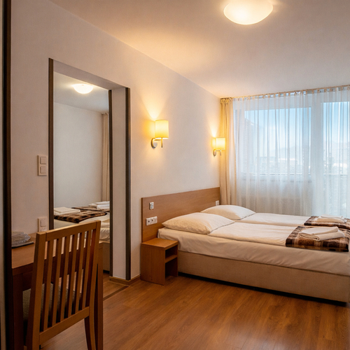 Przytulny pokój hotelowy z dwoma łóżkami obok siebie, drewnianym biurkiem, TV, zasłonami i złożonymi ręcznikami