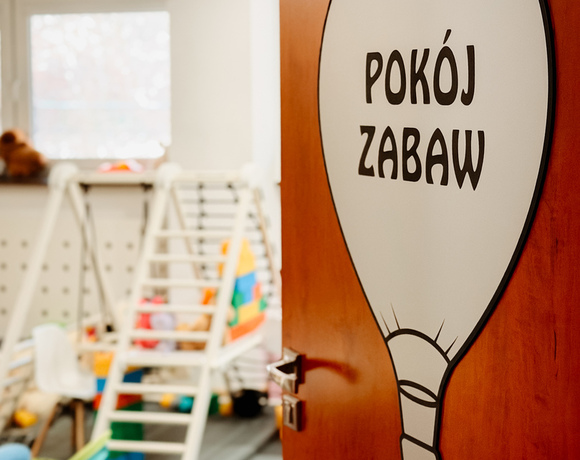 Hotelowy pokój zabaw z drewnianą drabinką, miękkimi matami, pluszakami i kolorowymi zabawkami — przytulna strefa dla dzieci.