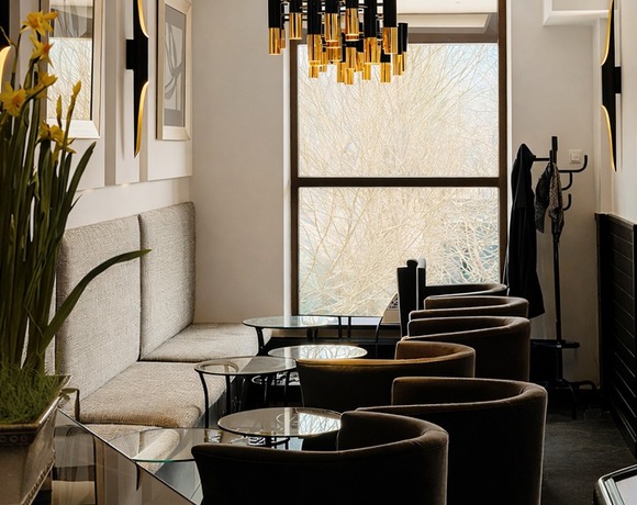 Elegancki hotelowy salon z przytulnymi fotelami, sofą przy ścianie, szklanymi stolikami i nowoczesnym złoto-czarnym żyrandolem