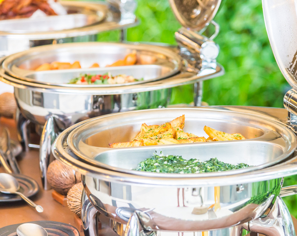 Pieczone ziemniaki w ćwiartkach i kremowy szpinak w błyszczących, podgrzewanych pojemnikach bufetowych