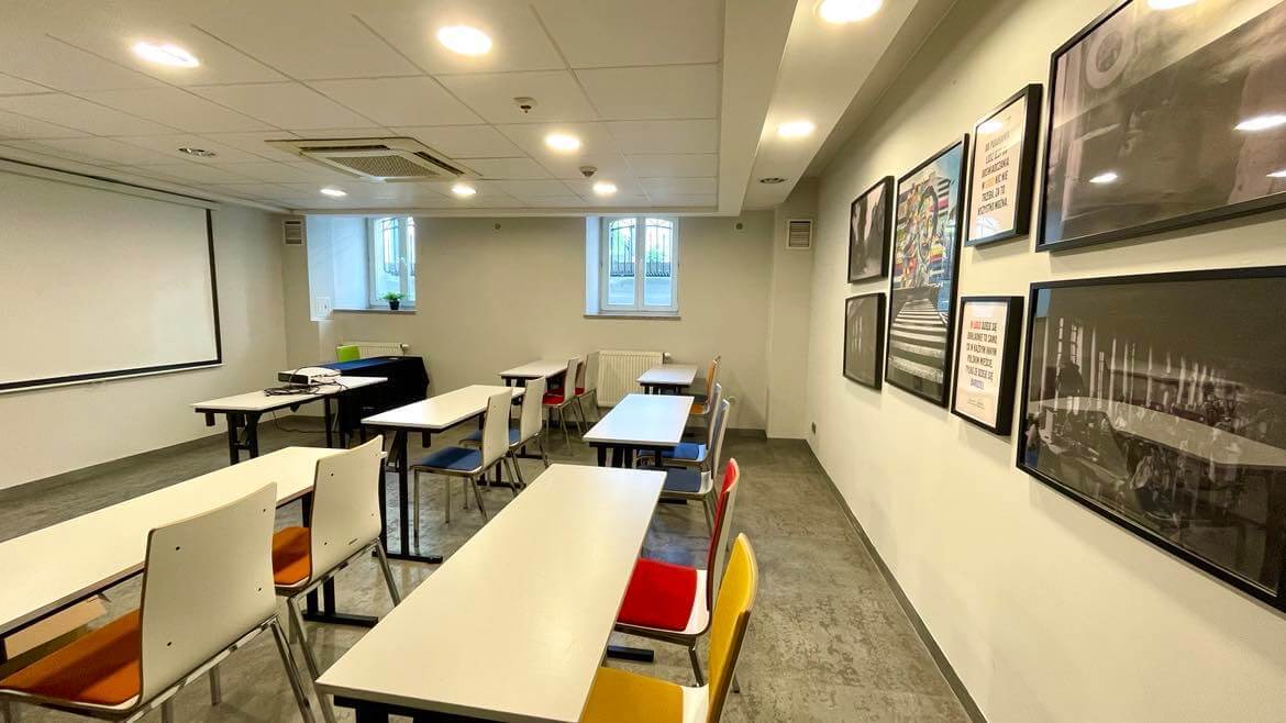 Sala konferencyjna z układem szkolnym stołów i krzeseł, przygotowana na szkolenie