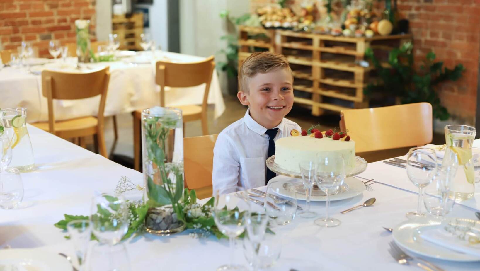 Uśmiechnięte dziecko podczas uroczystości rodzinnej odbywającej się w restauracji przy torcie