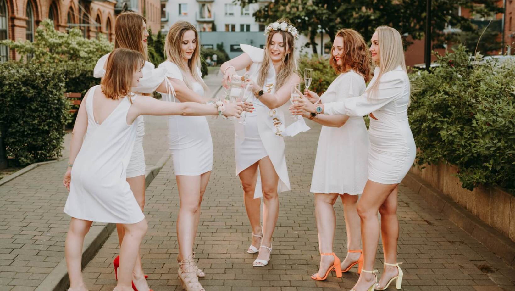 Group of friends celebrating by pouring champagne in the hotel courtyard