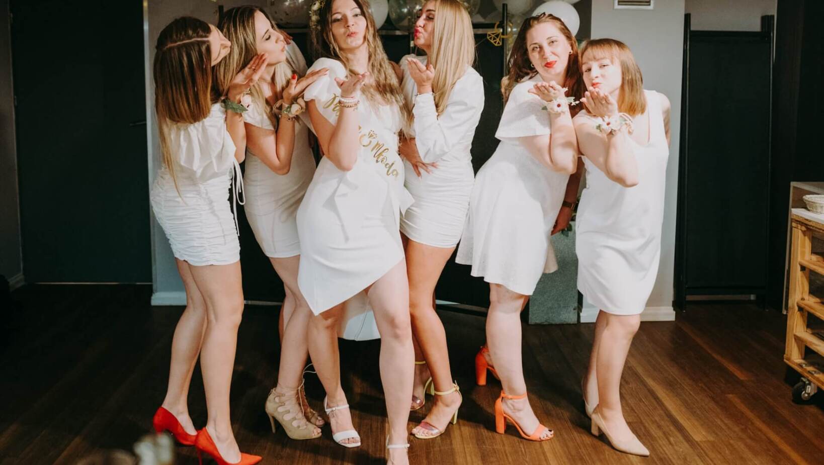 Group of friends in white dresses celebrating bachelorette party sending greetings