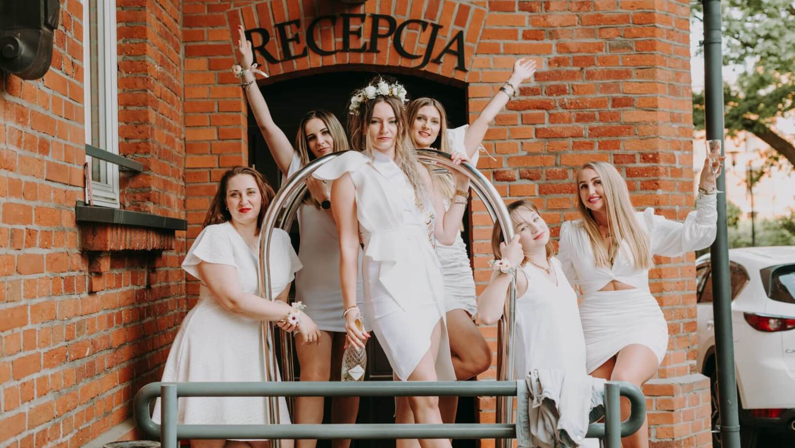 Group of friends dressed in white in front of the hotel reception entrance during bachelorette party