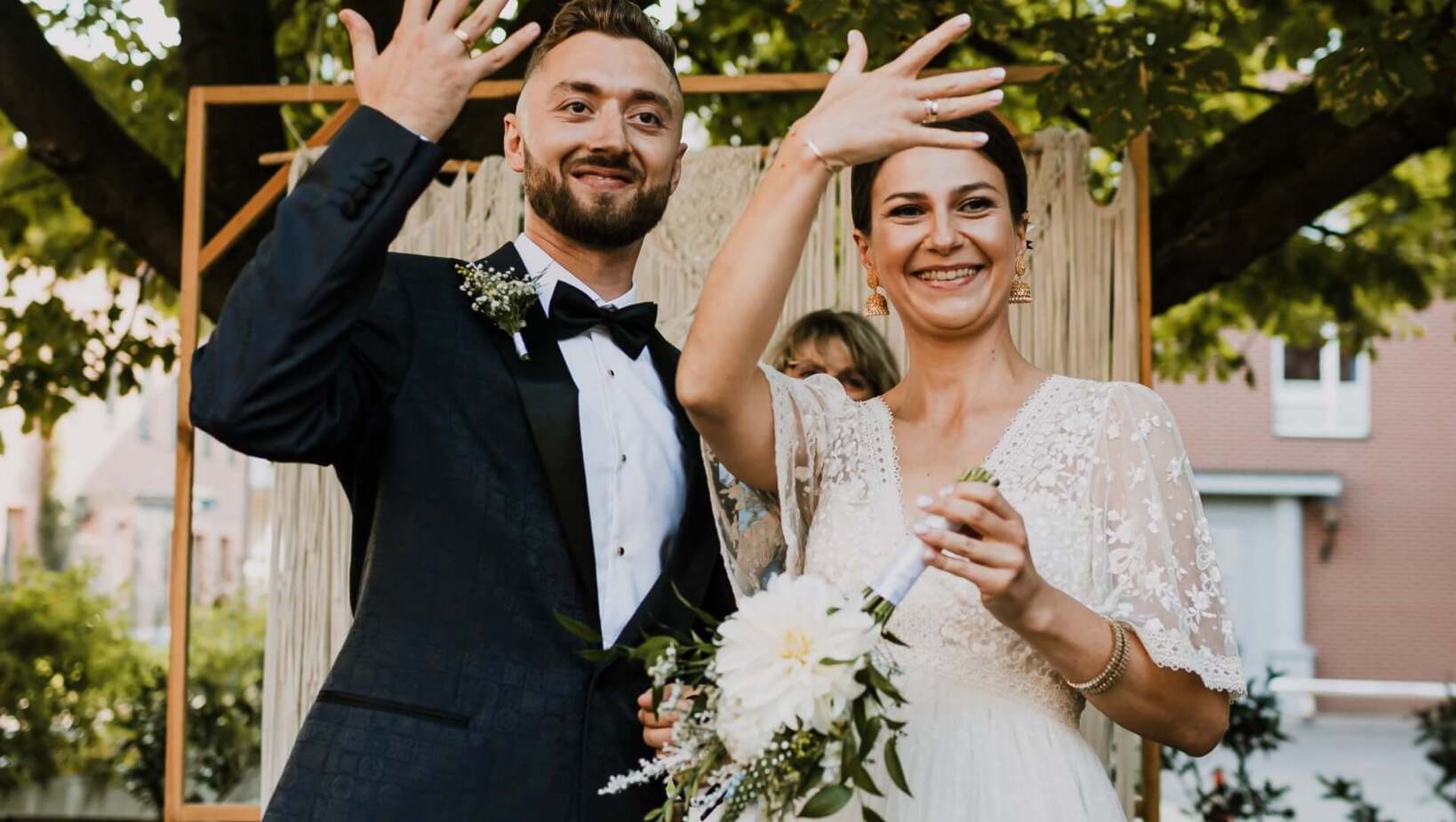 Państwo młodzi pokazują gościom swoje obrączki z radością