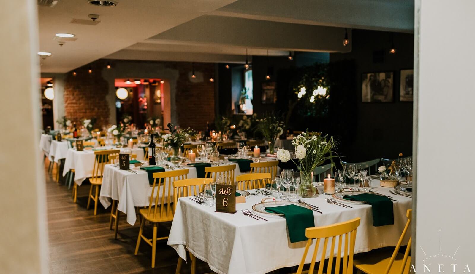 Przyjęcie weselne w kolorowej, ciepłej sali z kilkoma rzędami stołów