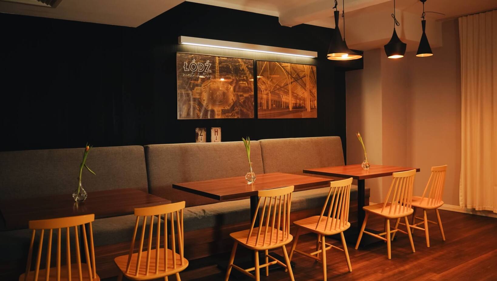 Ciepłe oświetlenie we wnętrzu restauracji w zaciszu stolików z krzesłami i sofą