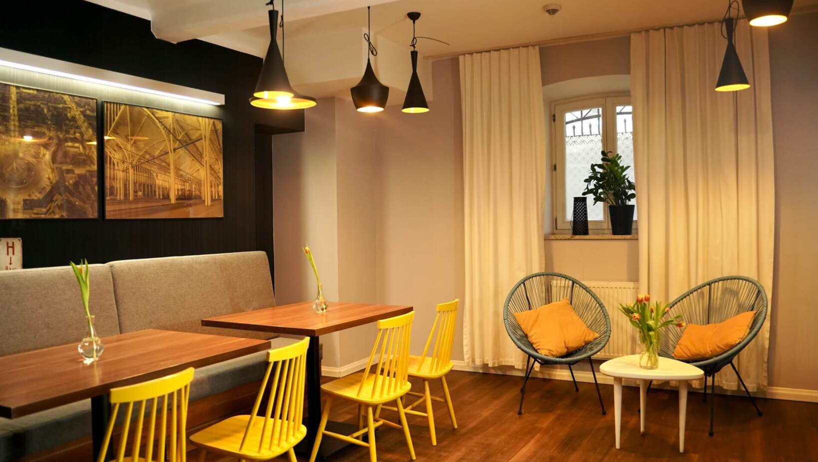 Ciepła i kameralna sala restauracyjna z małymi stołami i wygodnymi fotelami