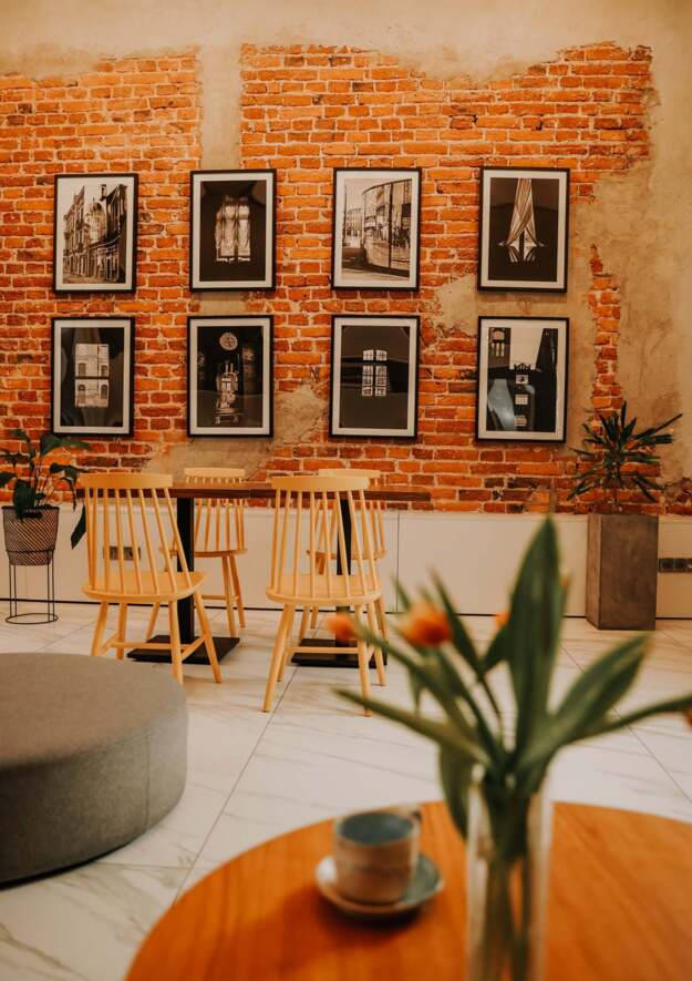 Stylish cafe in Tobaco Park Hotel with brick wall, photo gallery and wooden furniture