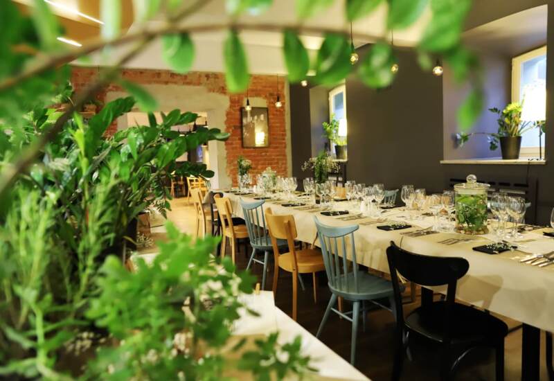 Long table in the restaurant elegantly set behind greenery decorating the dining room