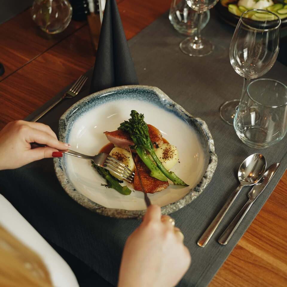 Guest in restaurant at Kretschmer’s tasting one of the elegantly prepared main dishes