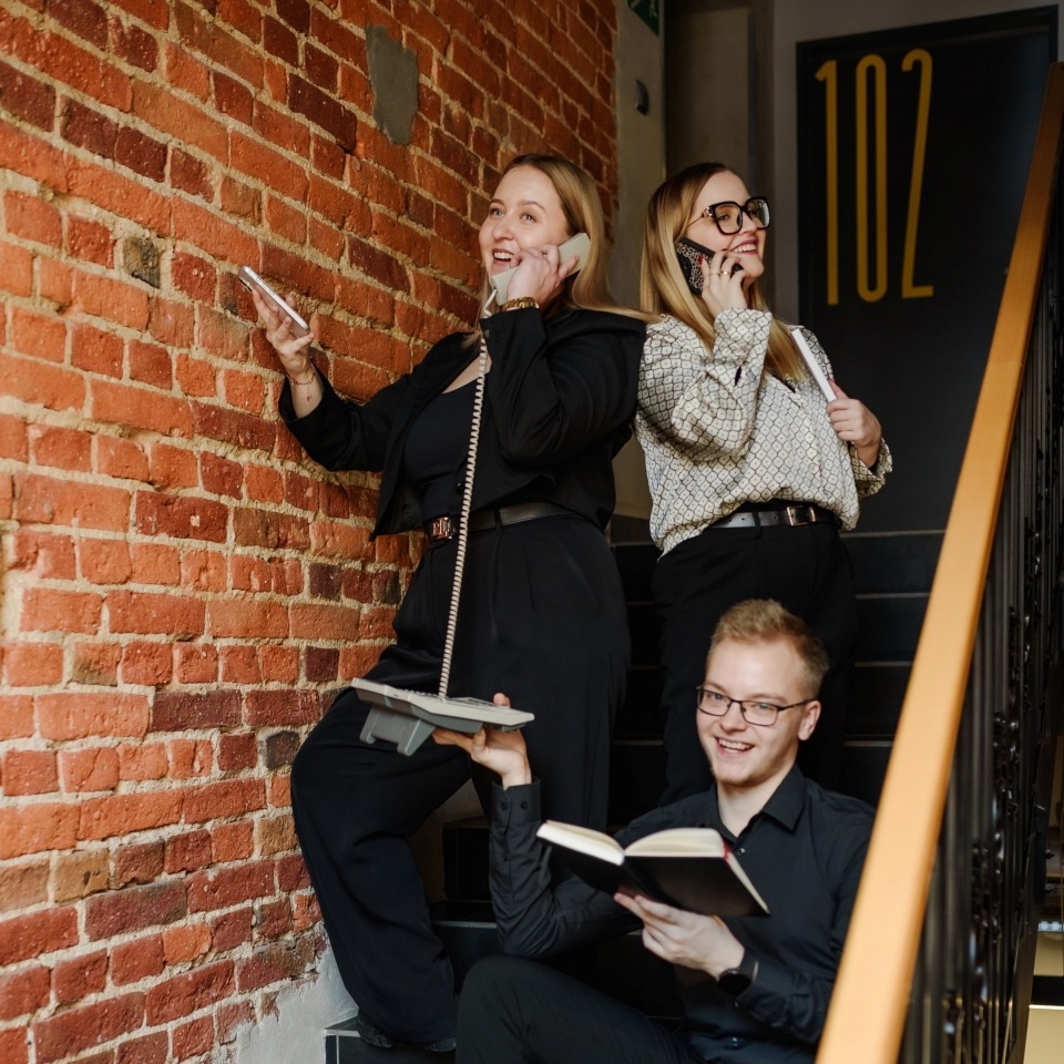 Pracownicy hotelowi w dobrych humorach, na schodach wykonujący telefony