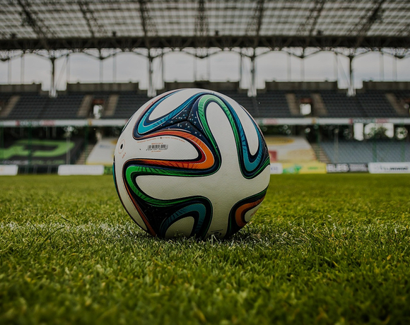 Match-ready soccer ball on manicured pitch with covered, empty stadium stands