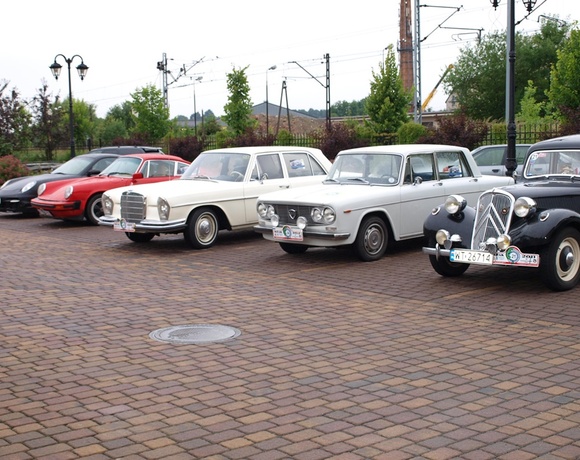 Row of vintage cars on a brick courtyard outside, classic car rally setting perfect for hotel events and photo spots