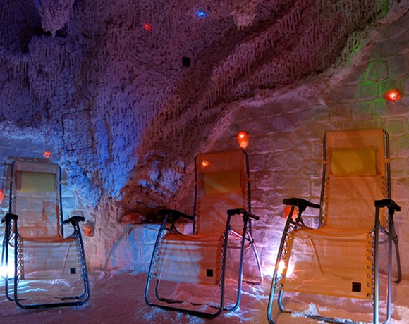 Salt-cave relaxation room with reclining lounge chairs, glowing Himalayan salt lamps and colored mood lighting