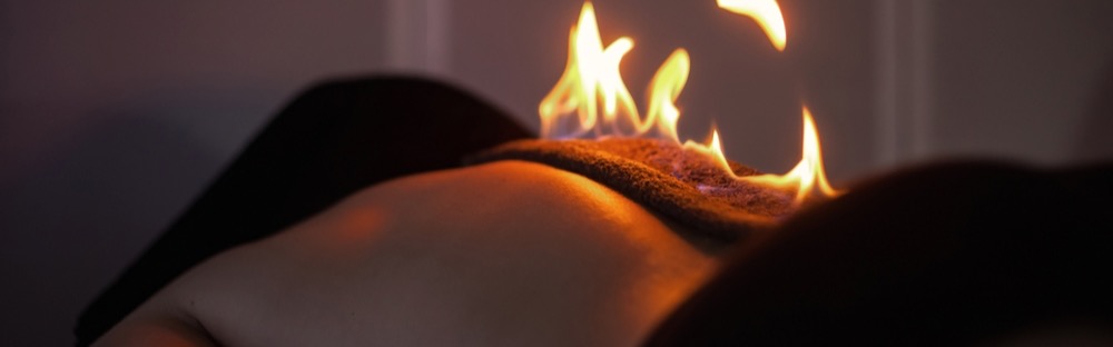 Relaksujący zabieg spa na plecach z ogniem na ręczniku, tworzący spokojną i terapeutyczną atmosferę.