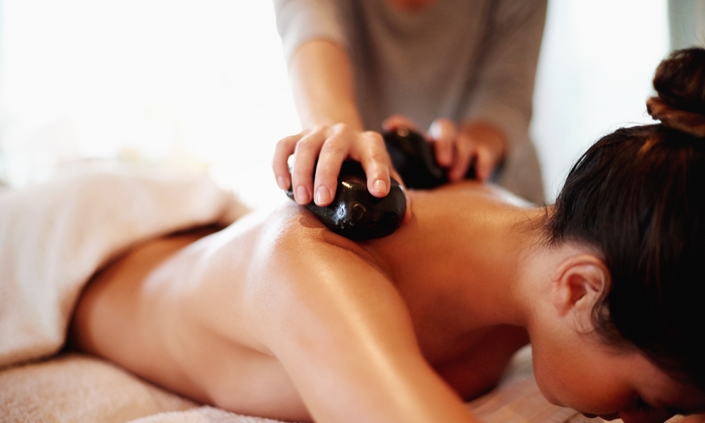 Relaksujący masaż gorącymi kamieniami w spa hotelowym, ciepła atmosfera i odprężenie mięśni szyi i pleców