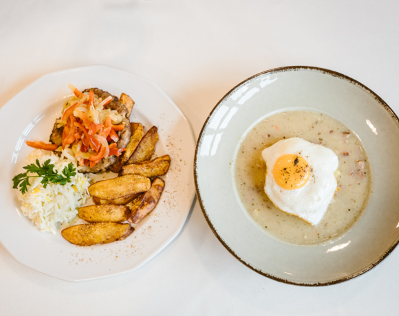 Tradycyjny posiłek z talerzem ziemniaków pieczonych, mielonym kotletem z duszonymi warzywami, sałatką i zupą z jajkiem sadzonym