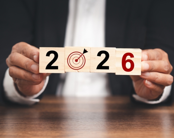 Osoba trzymająca drewniane kostki układające cyfrę 2026 z symbolem celu zamiast zera, reprezentujące planowanie i celowość.