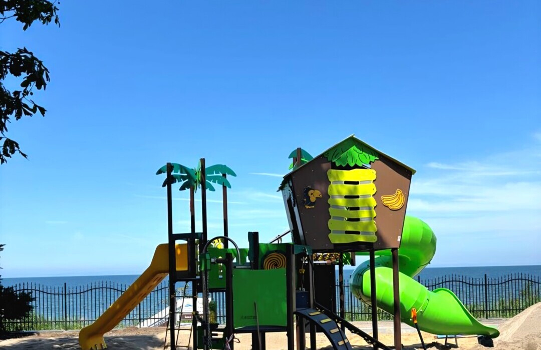 Plac zabaw z zjeżdżalniami w tropikalnym stylu na plaży z widokiem na morze i piasek.