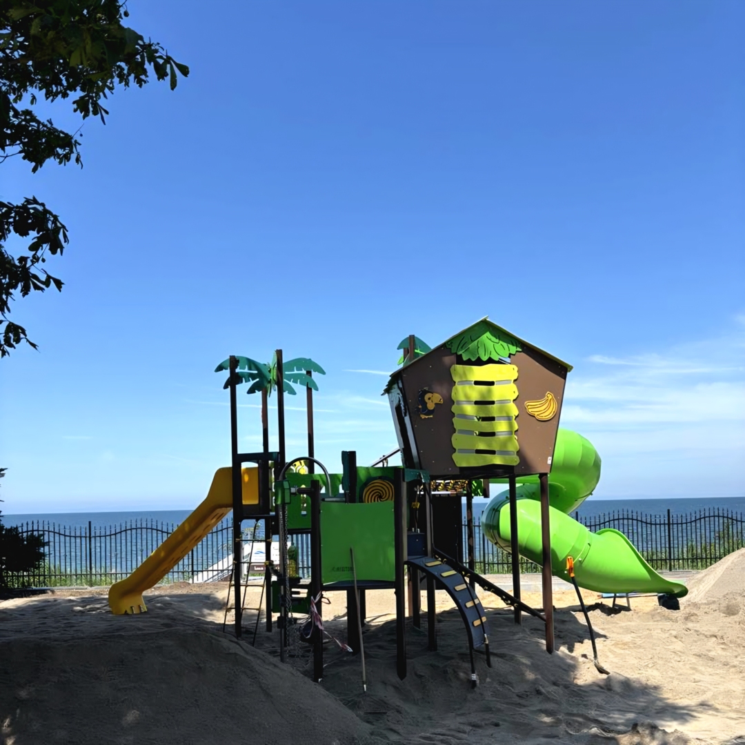 Plac zabaw dla dzieci z zjeżdżalniami i kolorowymi palmami przy plaży z widokiem na morze