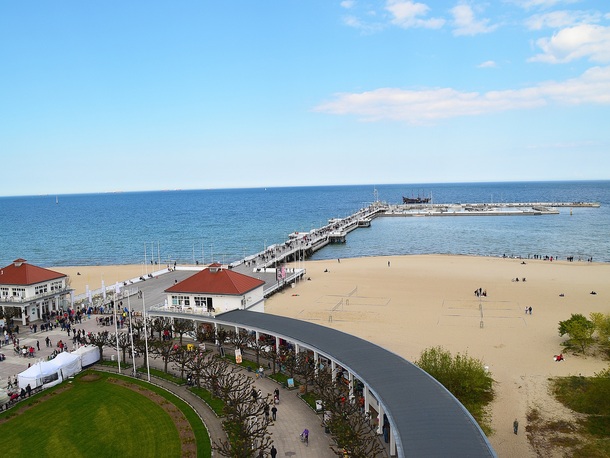 Piaszczysta plaża z ruchliwym deptakiem, czerwone dachy pawilonów i długie molo z gośćmi, spokojne morze i błękitne niebo. Drewniane molo w Sopocie – najdłuższy pomost w całej Europie, sięgający ponad 511 metrów w głąb Zatoki Gdańskiej. Białe balustrady, zapach morskiej bryzy i malownicza panorama na szeroką, złotą plażę oraz zabytkową architekturę. Serce i wizytówka słynnego kurortu.