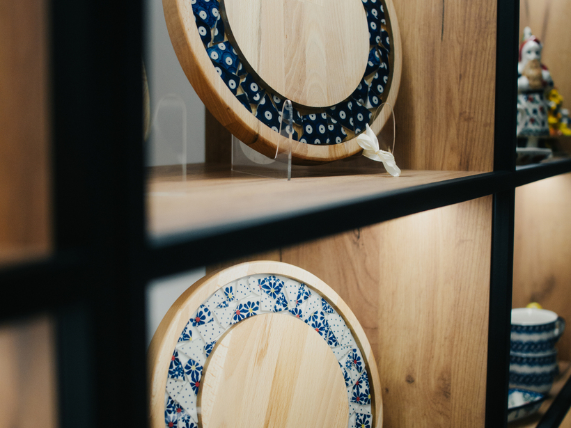 Drewniane deski do serwowania z niebieskim ceramicznym ornamentem, ekspozycja na drewnianej półce z ciepłym oświetleniem