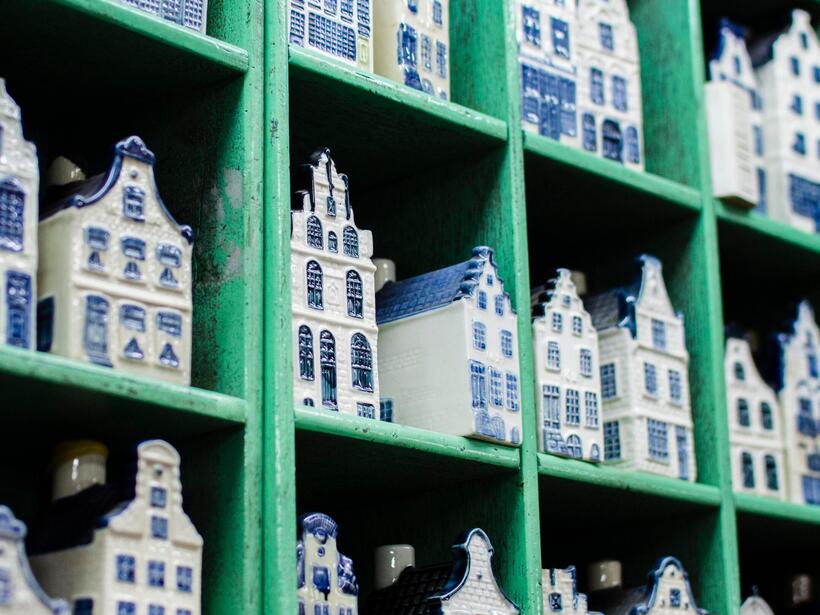Porcelanowe białe i niebieskie miniatury holenderskich kamienic - pamiątki ustawione w zielonych przegródkach